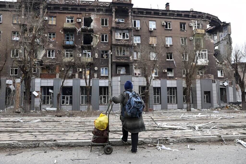 APTOPIX Ukraine Russia A person stands in front of a severely damaged building in Mariupol, Ukraine.