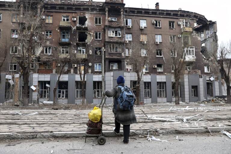 A person stands in front of a severely damaged building in Mariupol, Ukraine.