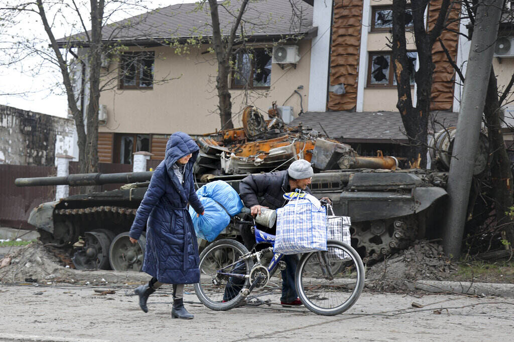 APTOPIX Russia Ukraine Local civilians walk past a tank destroyed during heavy fighting in Mariupol