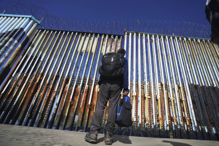 A migrant waits of the Mexican side of the border after United States Customs and Border Protection officers detained a couple of migrants crossing the U.S.-Mexico border on the beach, in Tijuana, Mexico, Wednesday, Jan. 26, 2022. (AP Photo/Marco Ugarte)