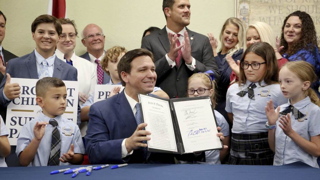 Florida Gov. Ron DeSantis displays the signed Parental Rights in Education, the so-called “Don’t Say Gay” bill, flanked by elementary school students during a news conference on Monday at Classical Preparatory school in Shady Hills, Fla. Florida Gov. Ron DeSantis displays the signed Parental Rights in Education, the so-called