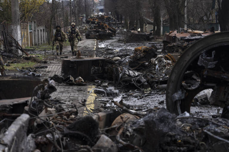 Soldiers walk amid destroyed Russian tanks in Bucha, in the outskirts of Kyiv, Ukraine, Sunday, April 3, 2022. Ukrainian troops are finding brutalized bodies and widespread destruction in the suburbs of Kyiv, sparking new calls for a war crimes investigation and sanctions against Russia.