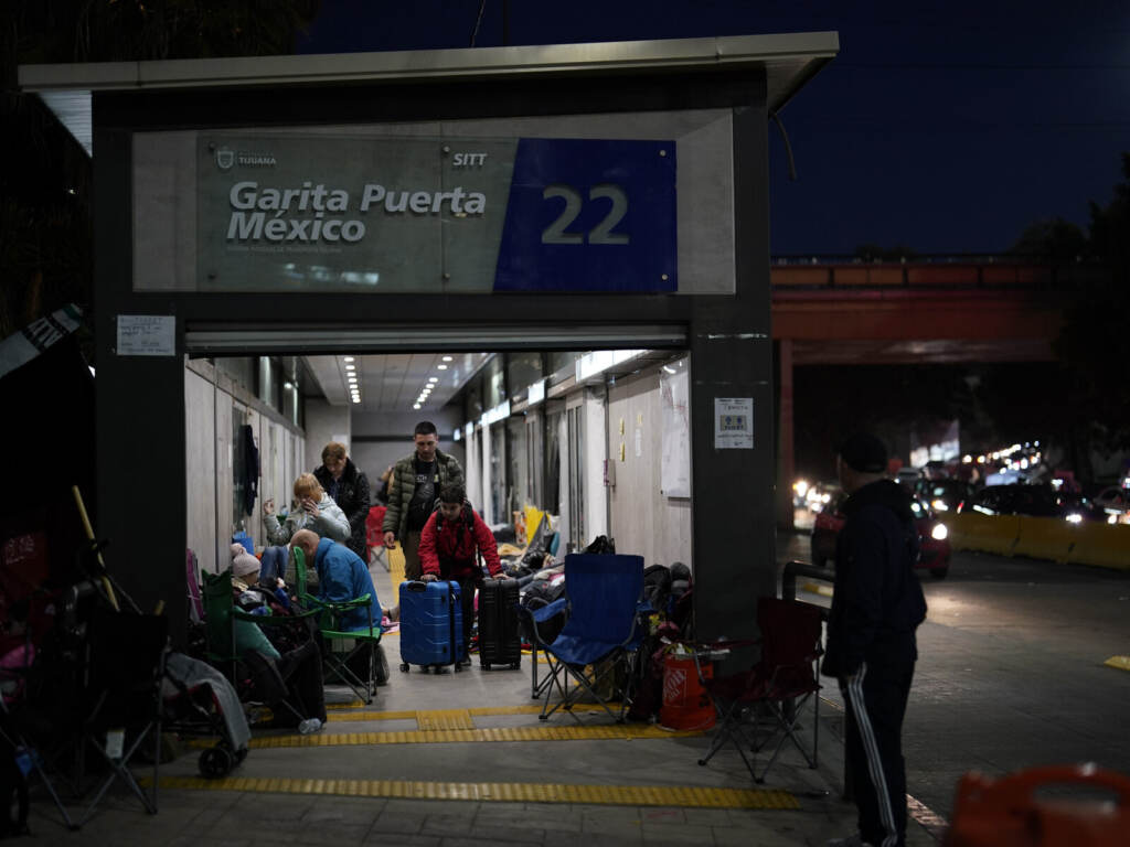 Ukrainian refugees wait in a bus stop near the border Monday, April 4, 2022, in Tijuana, Mexico.