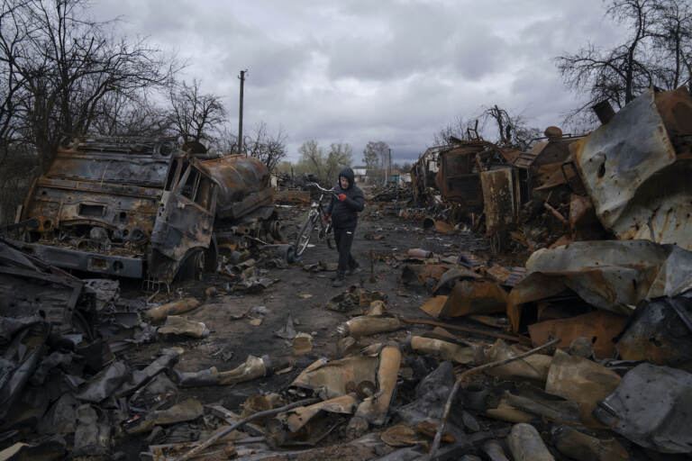 A man walks with a bicycle in a street with destroyed Russian military vehicles near Chernihiv