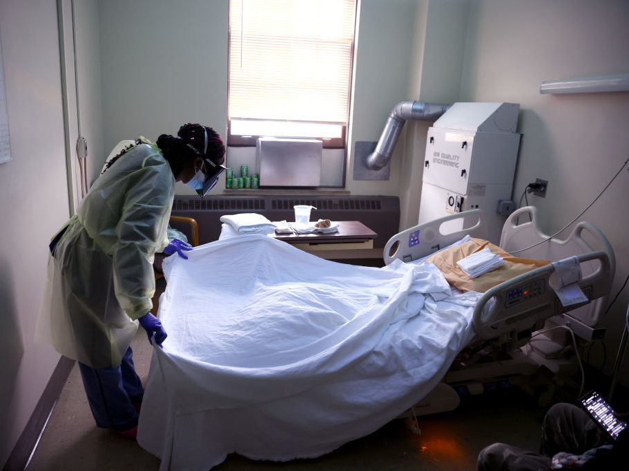 The continued death toll from COVID led to another drop in life expectancy in 2021. Tanetshia Brown changes bed linens for a COVID-19 patient