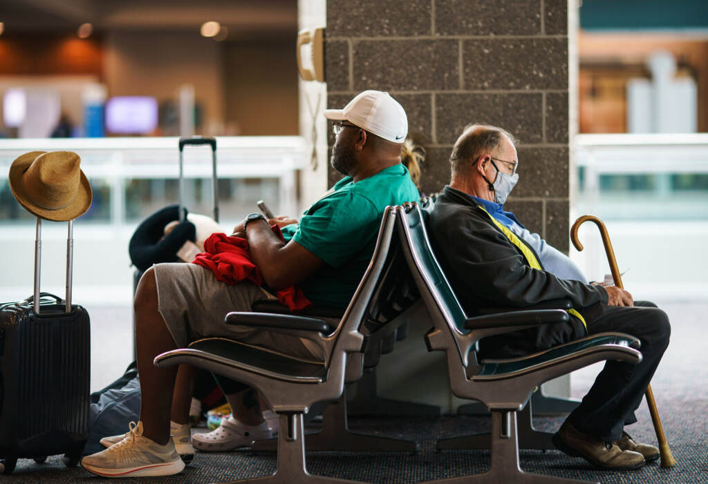 Travel Mask Mandate Travelers sit in a waiting area at Rhode Island T.F. Green International Airport