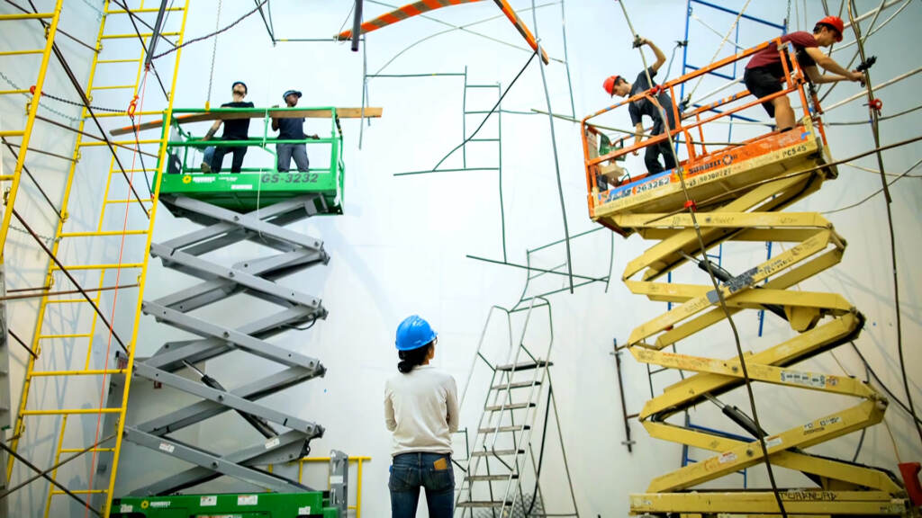 m&m-Michelle-Lopez Artist Michelle Lopez wearing a construction helmet observing people on lifts installing her sculptures