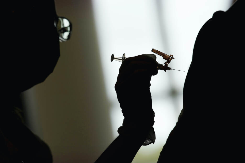 Virus Outbreak Vaccines Kids A silhouette of a health worker administering a COVID-19 vaccine