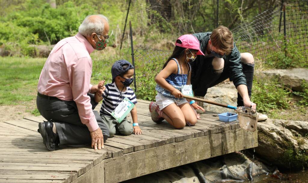naturepalooza-schuylkill-center-for-environmental-education-041822 Two adults sit with two children on a Schuylkill River dock
