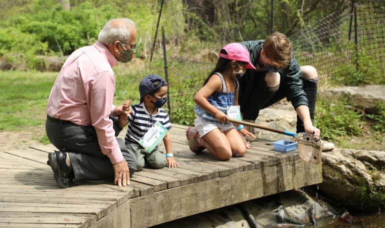 Two adults sit with two children on a Schuylkill River dock