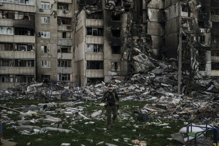 A Ukrainian serviceman walks amid the rubble of a building heavily damaged by multiple Russian bombardments