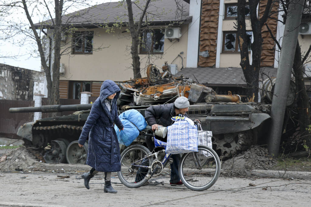 APTOPIX Russia Ukraine Local civilians walk past a tank destroyed during heavy fighting in Mariupol