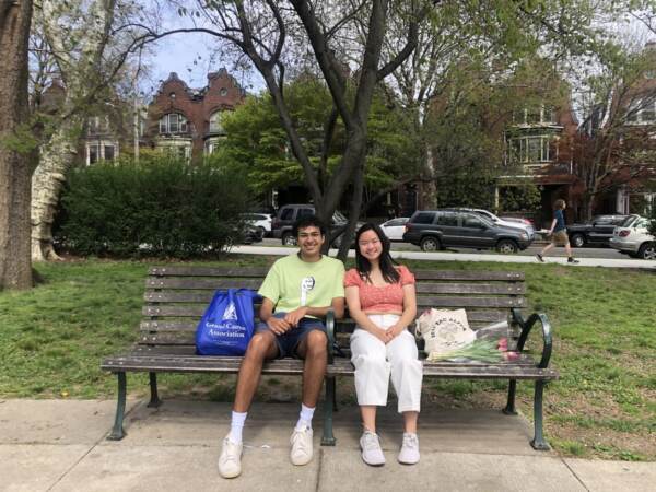 Megan Li and Imran Siddiqui, undergrad students at the University of Pennsylvania, enjoying the sun at Clark Park. Li has plans with her family this holiday weekend but they’re staying outdoors to stay COVID safe. (Emily Rizzo/WHYY News)
