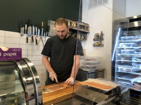 Joey Powell slicing salmon at Biederman’s in South Philadelphia. Powell said they had a surge in online orders for Passover and Easter. (Emily Rizzo/WHYY News)