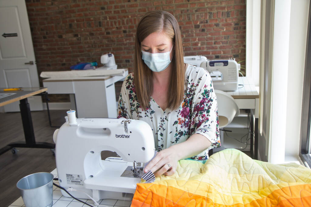 2022 05 25 k paynter cut & sew (1 of 1)-9 Melissa Clouser, owner of Cut & Sew, edges a quilt top she made with students to be donated to a refugee family. (Kimberly Paynter/WHYY)