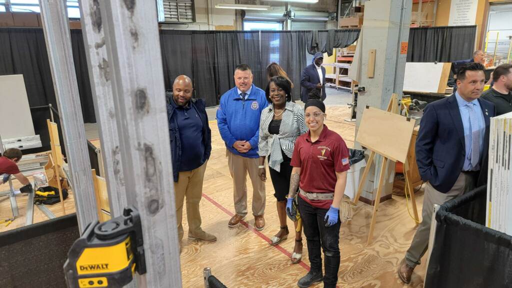 20220506_102122 Apprentice Priscilla Torres (center, in red) stands with (left to right) Councilmember Cherelle Parker, Carpenters Union Head William Sproule and Ryan Boyer, who runs the Building Trades Council. (Tom MacDonald/WHYY)