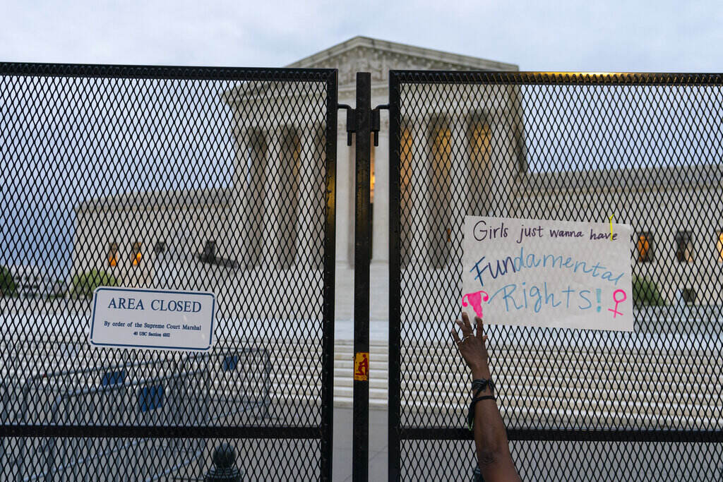 Supreme Court Abortion A demonstrator places a sign on the anti-scaling fence outside of the U.S. Supreme Court Thursday, May 5, 2022 in Washington. A draft opinion suggests the U.S. Supreme Court could be poised to overturn the landmark 1973 Roe v. Wade case that legalized abortion nationwide, according to a Politico report released Monday. (AP Photo/Alex Brandon)