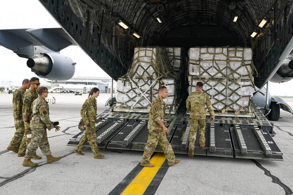 Tom Vilsack Crew members walk up a ramp to where boxes of baby formula are stacked.