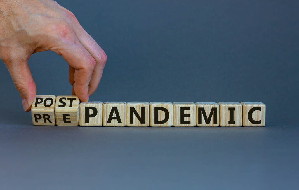 Hand turns cubes and changes the words 'pre-pandemic' to 'post-pandemic'.