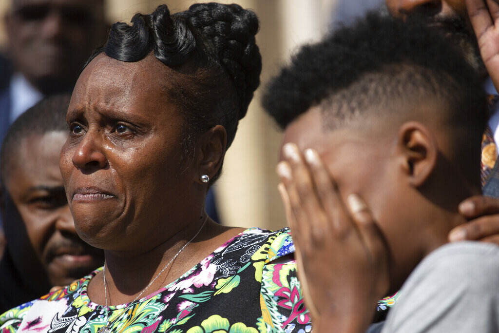 CORRECTION Buffalo Supermarket Shooting Food Desert A young boy hides his face in his hands, while a woman in the background holds back tears.