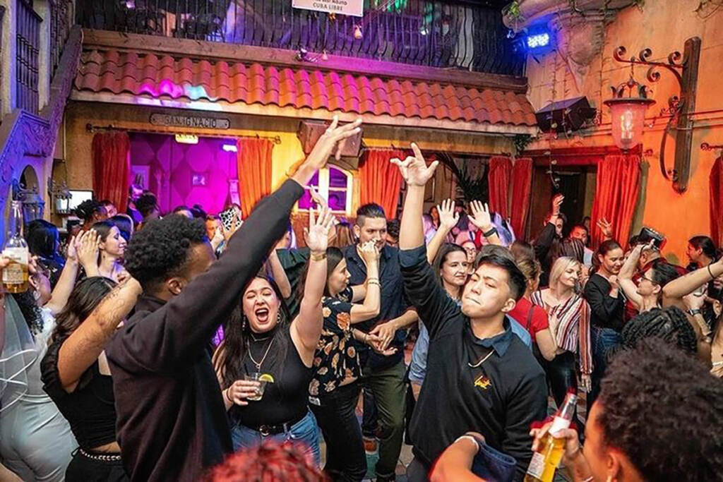 cubalibre-nightlife-dancing People are dancing with their arms up, and colorful lights in the background.