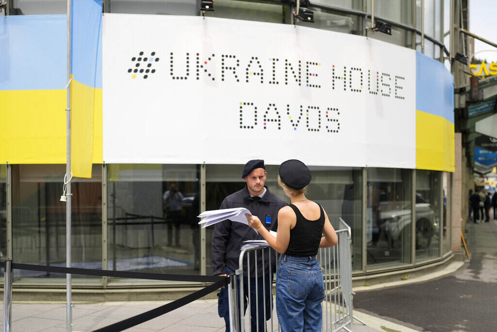 Switzerland Davos Forum A security guard talks to a women in front of the Ukrainian House alongside the World Economy Forum in Davos, Switzerland, Sunday, May 22, 2022. The annual meeting of the World Economy Forum is taking place in Davos from May. 22 until May. 26, 2020.