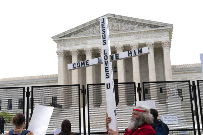 File photo: A demonstrator holding a cross protests outside of the U.S. Supreme Court, Thursday, May 5, 2022, in Washington.