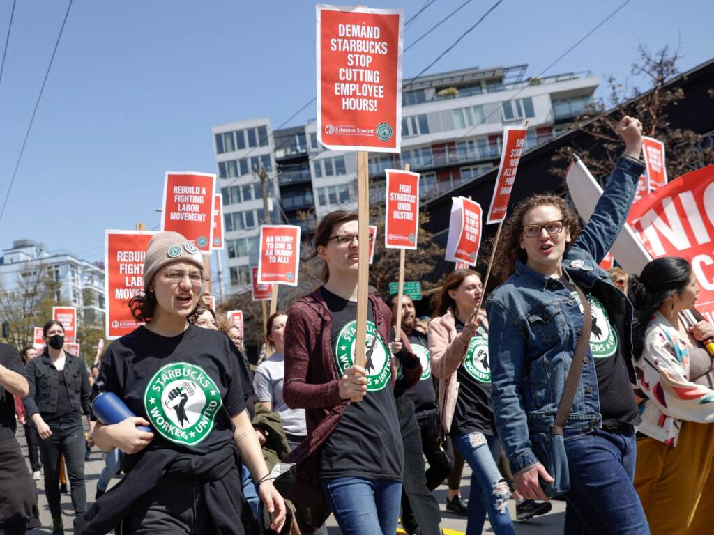 Protesters march in Seattle during the “Fight Starbucks’ Union Busting” rally and march on April 23, 2022. Starbucks union supporters march with signs.