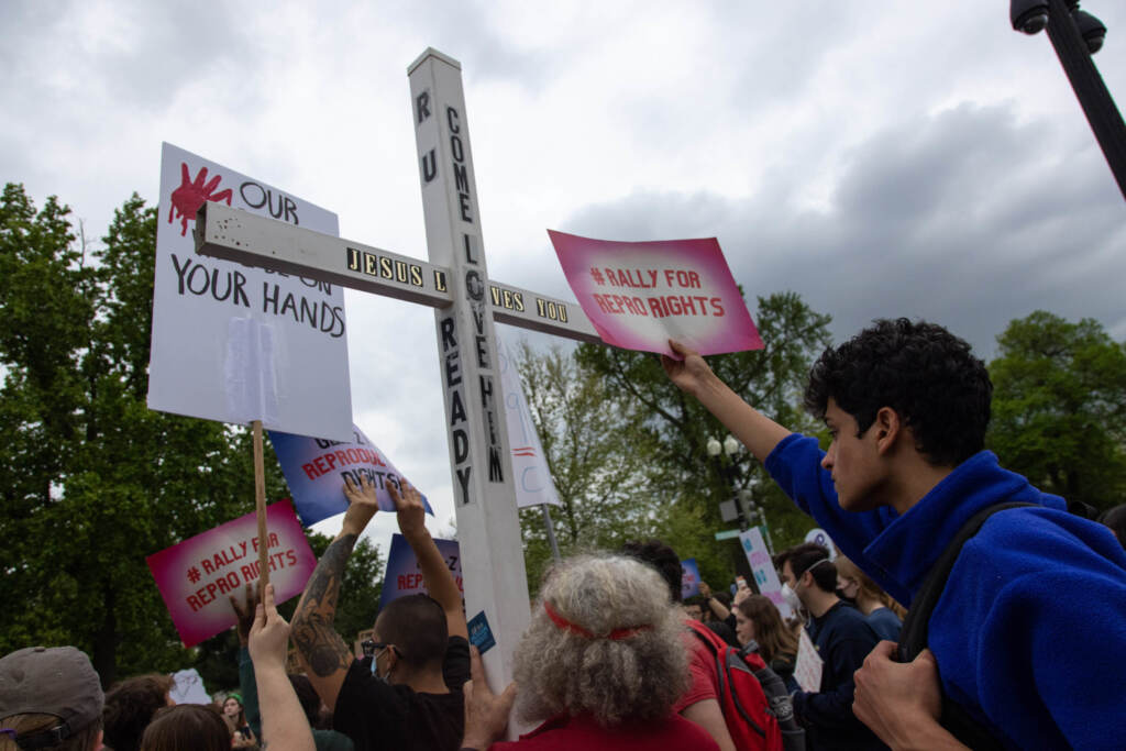 A counter-protestor holds a large cross during a youth pro-abortion rights rally outside of the Supreme Court in Washington, D.C., on May 5, following the leak of a draft Supreme Court opinion to overturn Roe v. Wade. A counter-protestor holds a large cross during a youth pro-abortion rights rally outside of the Supreme Court in Washington, D.C., on May 5, following the leak of a draft Supreme Court opinion to overturn Roe v. Wade.