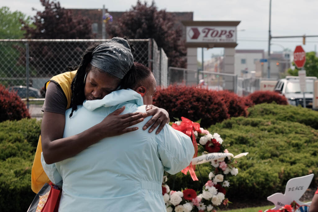 People embrace near a memorial for the shooting victims outside of Tops grocery store on May 20, 2022 in Buffalo, New York. Two people embrace in front of a memorial to victims of the Buffalo supermarket shooting.