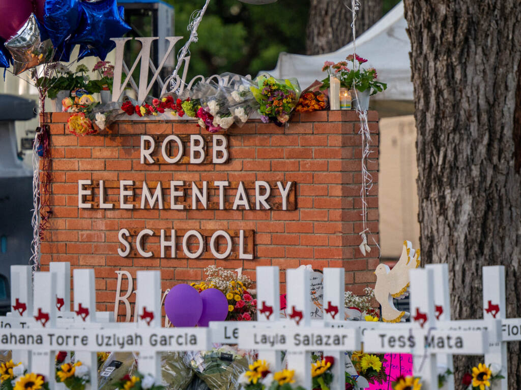 Mass Shooting At Elementary School In Uvalde, Texas Leaves At Least 21 Dead A memorial in front of a sign saying Robb Elementary School.