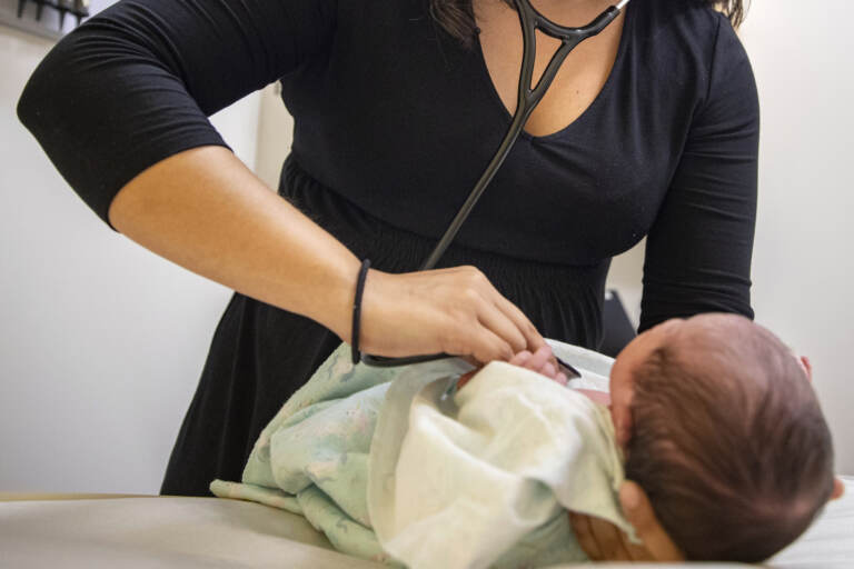 A pediatrician examines a newborn baby