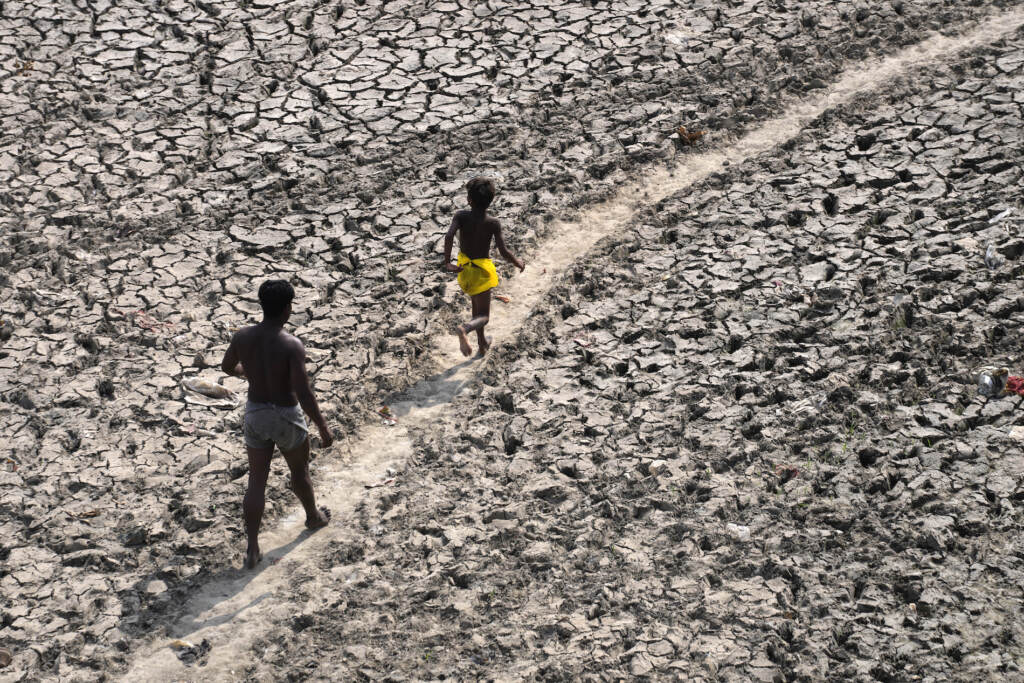 Climate Global Temperature 1.5 FILE - A man and a boy walk across the almost dried up bed of river Yamuna following hot weather in New Delhi, India, Monday, May 2, 2022. According to a report released by the World Meteorological Organization on Monday, May 9, 2022, the world is creeping closer to the warming threshold international agreements are trying to prevent, with nearly a 50-50 chance that Earth will temporarily hit that temperature mark within the next five years. (AP Photo/Manish Swarup, File)
