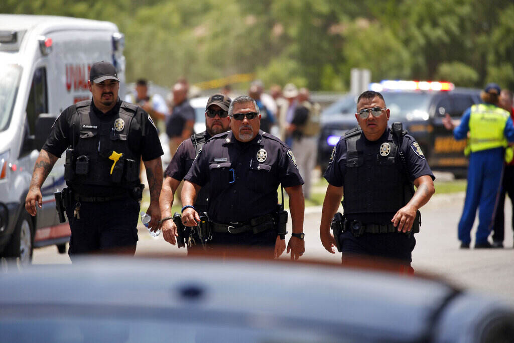 APTOPIX Texas School Shooting Three police officers walk towards a car.