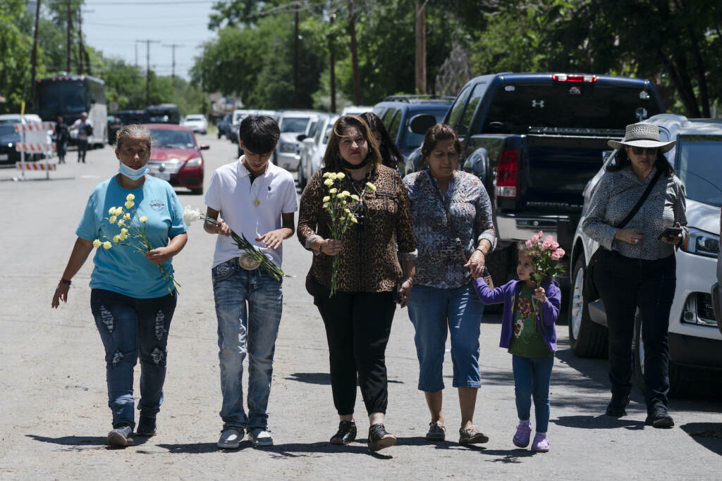 People walk with flowers to honor the victims of the Uvalde mass shooting