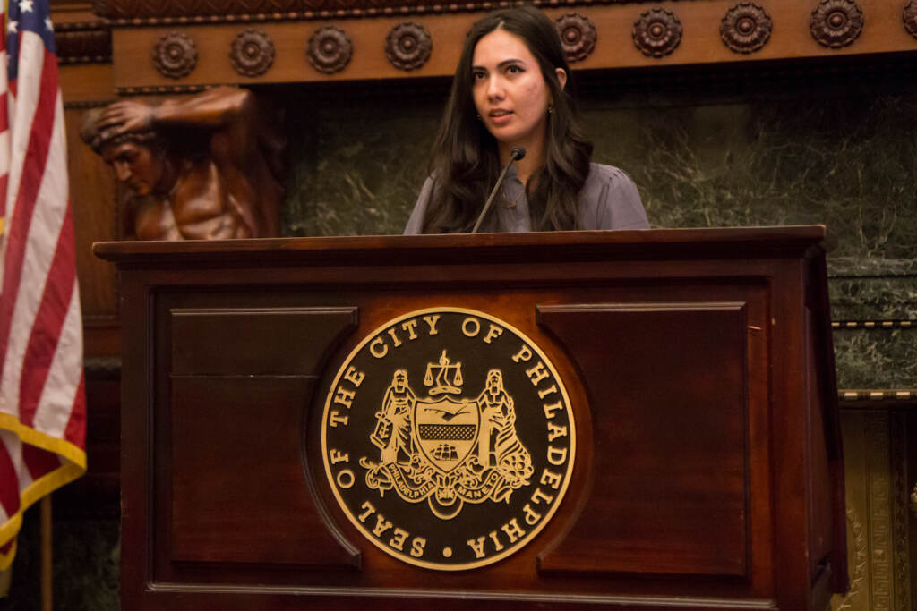 Farwa Ahmadi speaks from a podium at City Hall