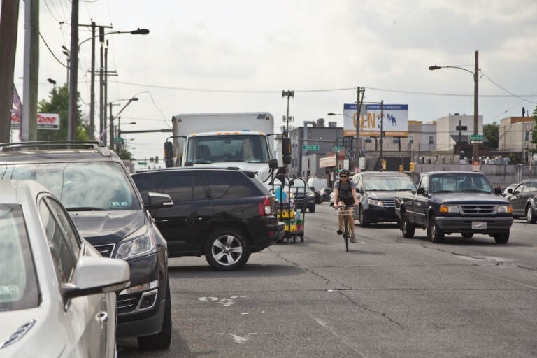 A cyclist navigates around a car and delivery truck on Washington Avneue.