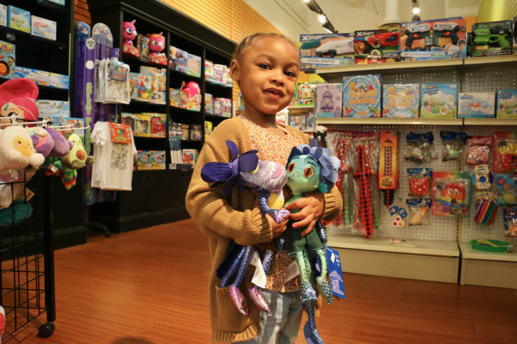 Sa'Niya Newsome holds two plush Disney toys inside the Heart of Hustle store