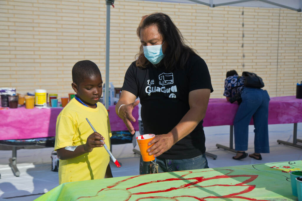 2022 06 24 kpaynter la guagua 47 bus decorating (1 of 1)-8 Mural Arts’ Cesar Viveros (right), worked with the North Philadelphia community to create a bus wrap celebrating La Guagua 47 Community Film and Arts Project on June 24, 2022. (Kimberly Paynter/WHYY)