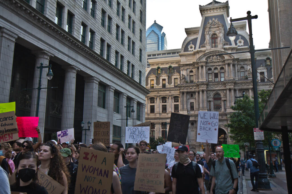 2022 06 24 kpaynter roe v. wade overturn protest (2 of 9) A large crowd of people demonstrates, holding signs, with City Hall visible in the background.