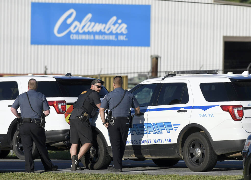 APTOPIX Shooting Maryland Police stand near where a man opened fire at a business, killing three people before the suspect and a state trooper were wounded in a shootout, according to authorities, in Smithsburg, Md., Thursday, June 9, 2022. The Washington County (Md.) Sheriff's Office said in a news release that three victims were found dead at Columbia Machine Inc. and a fourth victim was critically injured. (AP Photo/Steve Ruark)