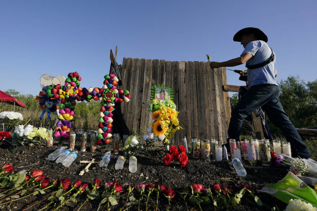 Roberto Marquez Roberto Marquez of Dallas adds a flower a makeshift memorial at the site where officials found dozens of people dead in an abandoned semitrailer containing suspected migrants, Wednesday, June 29, 2022, in San Antonio. (AP Photo/Eric Gay)