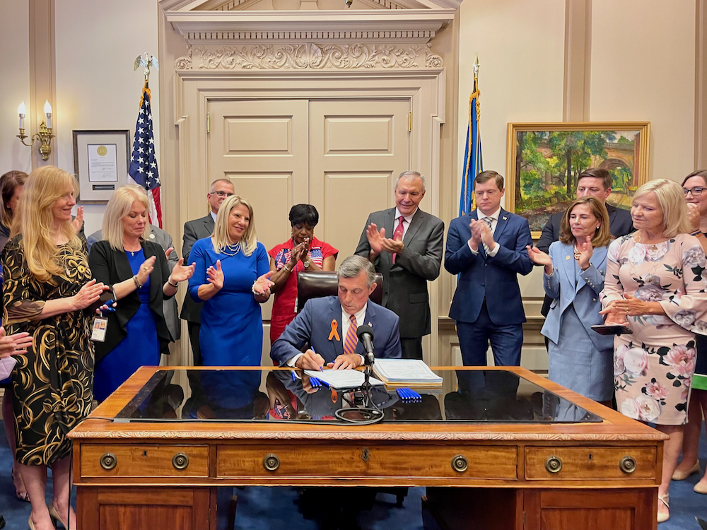 Signage Delaware Gov. John Carney signs a package of gun safety bills. (Johnny Perez-Gonzalez/WHYY)