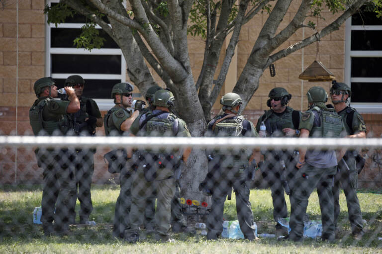 Law enforcement personnel stand outside Robb Elementary School following a shooting on May 24 in Uvalde, Texas. When the gunman arrived at the school, he hopped its fence and easily entered through an unlocked back door, police said. (Dario Lopez-Mills/AP)