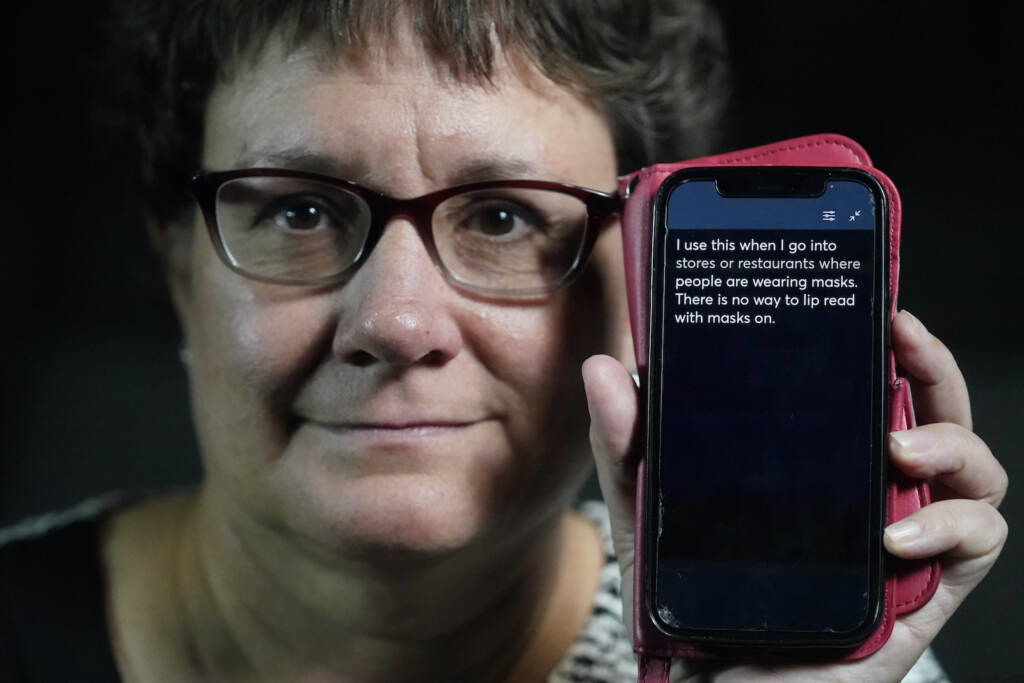 Hearing Loss Captions Everywhere Chelle Wyatt holds up a cell phone displaying the Otter app, with a message that reads, ''I use this when I go into stores or restaurants where people are wearing masks. There is no way to lip read with masks on.''