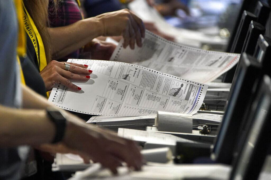 Supreme Court Elections Close-up of election workers' hands handling ballots.