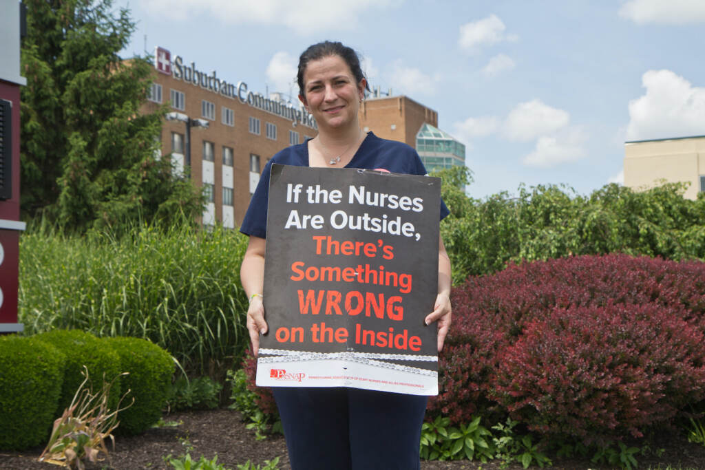 Kristin Law holds a protest sign outside Suburban Community Hospital