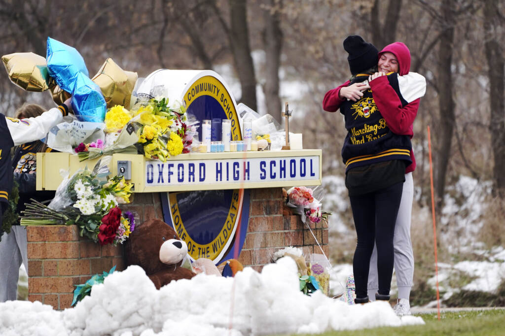 Students hug at a memorial at Oxford High School in Oxford, Mich., Dec. 1, 2021.