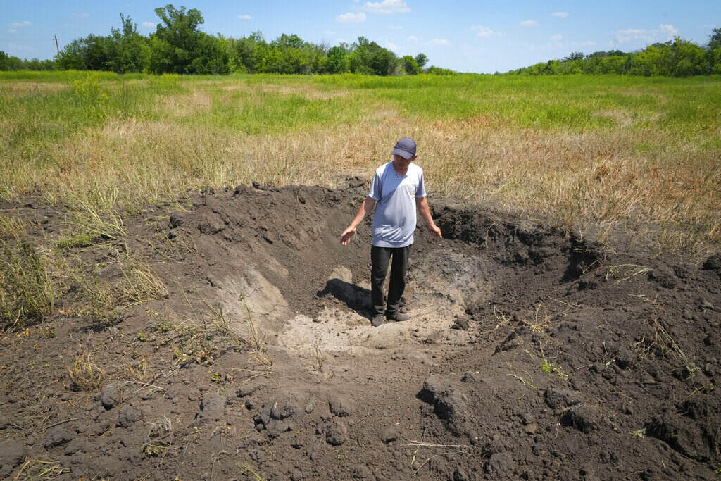 Russia Ukraine War Farmer Serhiy, a local grain producer, shows a crater left by a Russian shell on his field in the village of Ptyche in eastern Donetsk region, Ukraine, Sunday, June 12, 2022. Serhiy claims he cannot sell his grains because nobody wants to come to the area which has been under Russian shelling. Ukraine is one of the world’s largest exporters of wheat and corn but Russia's invasion and a blockade of its ports have halted much of that flow.