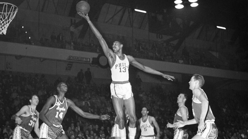 Wilt Chamberlain,Wilt the Stilt Wilt Chamberlain stretches up to make a basket in a black-and-white photo from 1961.